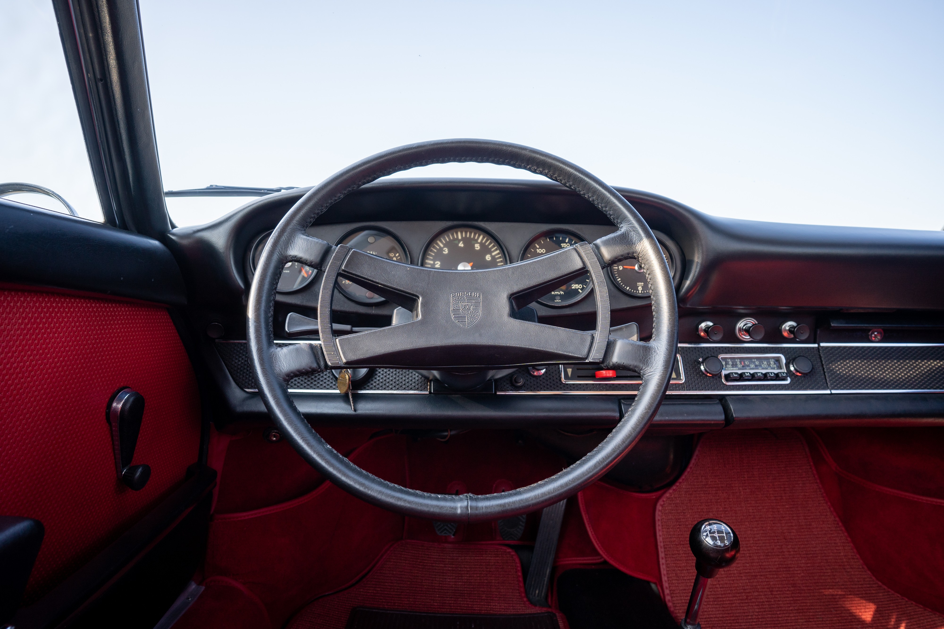 Steering wheel of a 1969 Porsche 911S in Ossi Blue over Red leatherette in Austin, TX.