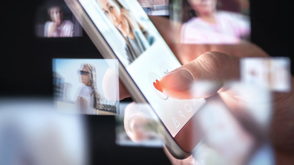 Person swiping through dating app profiles on a smartphone, symbolizing online dating, catfishing, and romance scams.