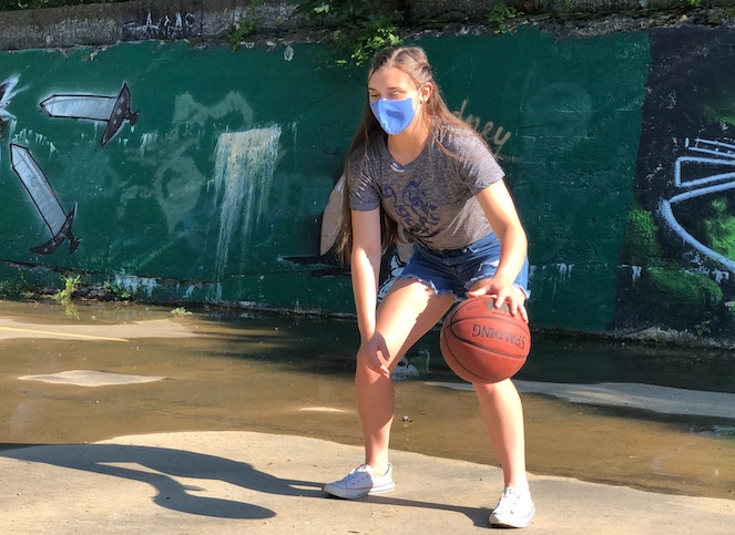 Young girl dribbling at outdoor basketball court on a sunny day