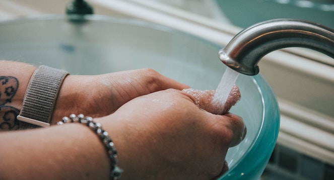 Woman's hands washing under a running faucet