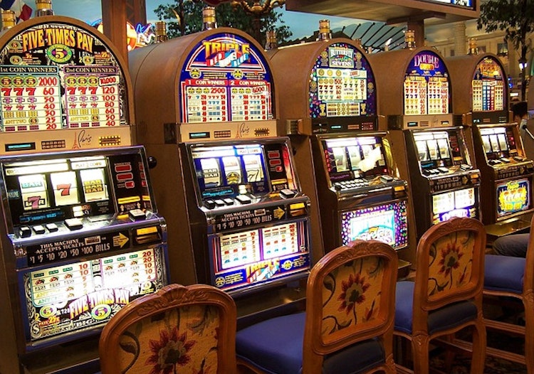 Row of brightly lit slot machines inside a casino, representing the popularity of mythology-themed slot games and their immersive visual appeal.