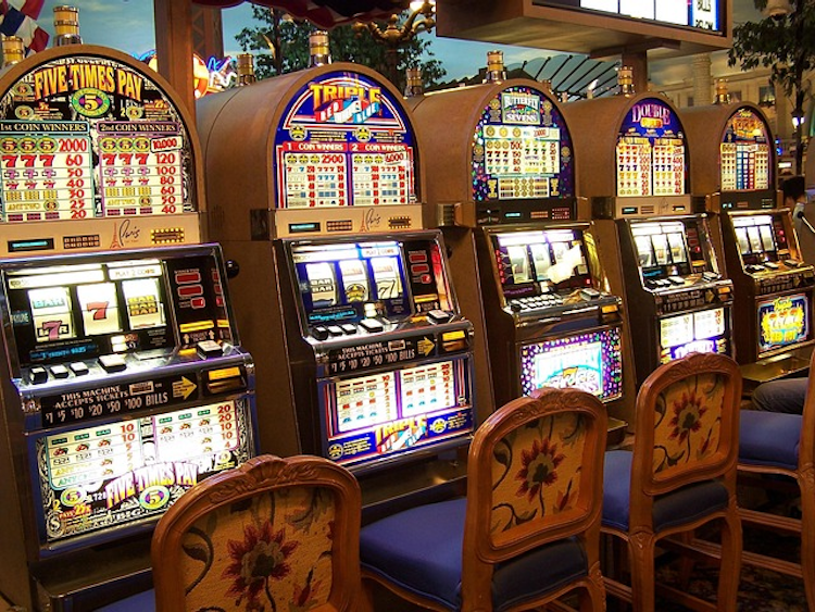 Row of brightly lit slot machines inside a casino, representing the popularity of mythology-themed slot games and their immersive visual appeal.