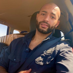 Daniel, a hispanic man in his 30s, sits in his car on a sunny day.