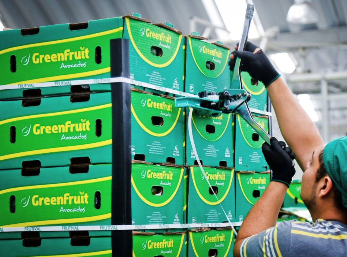 Moving boxes of GreenFruit Avocados on the warehouse floor.