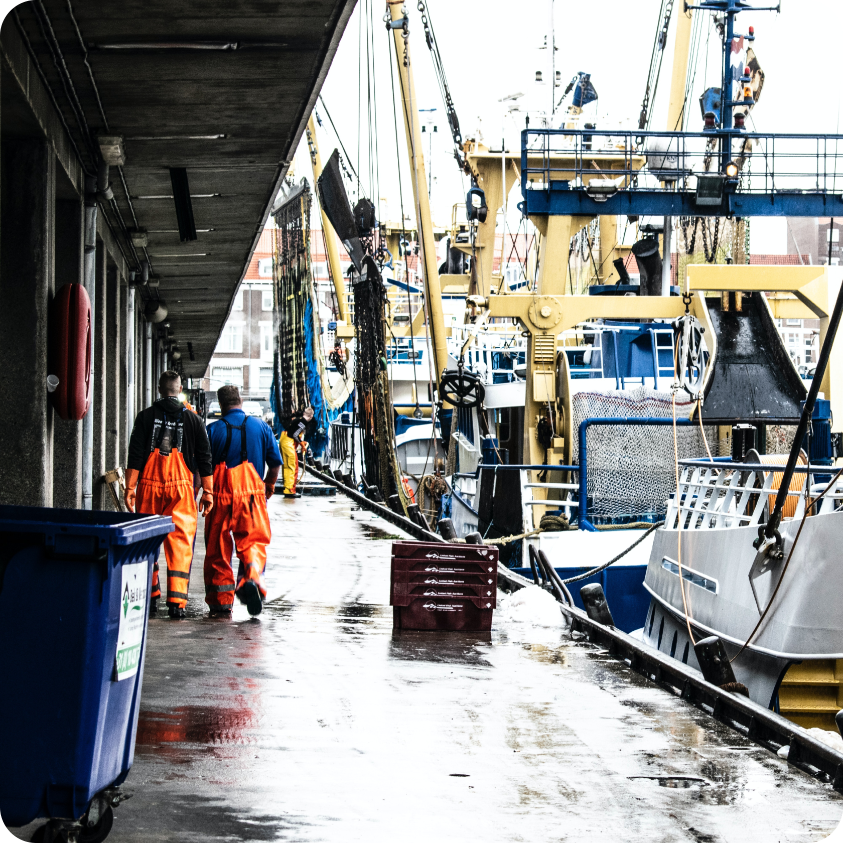 Two fisherman workers on the deck of a port.