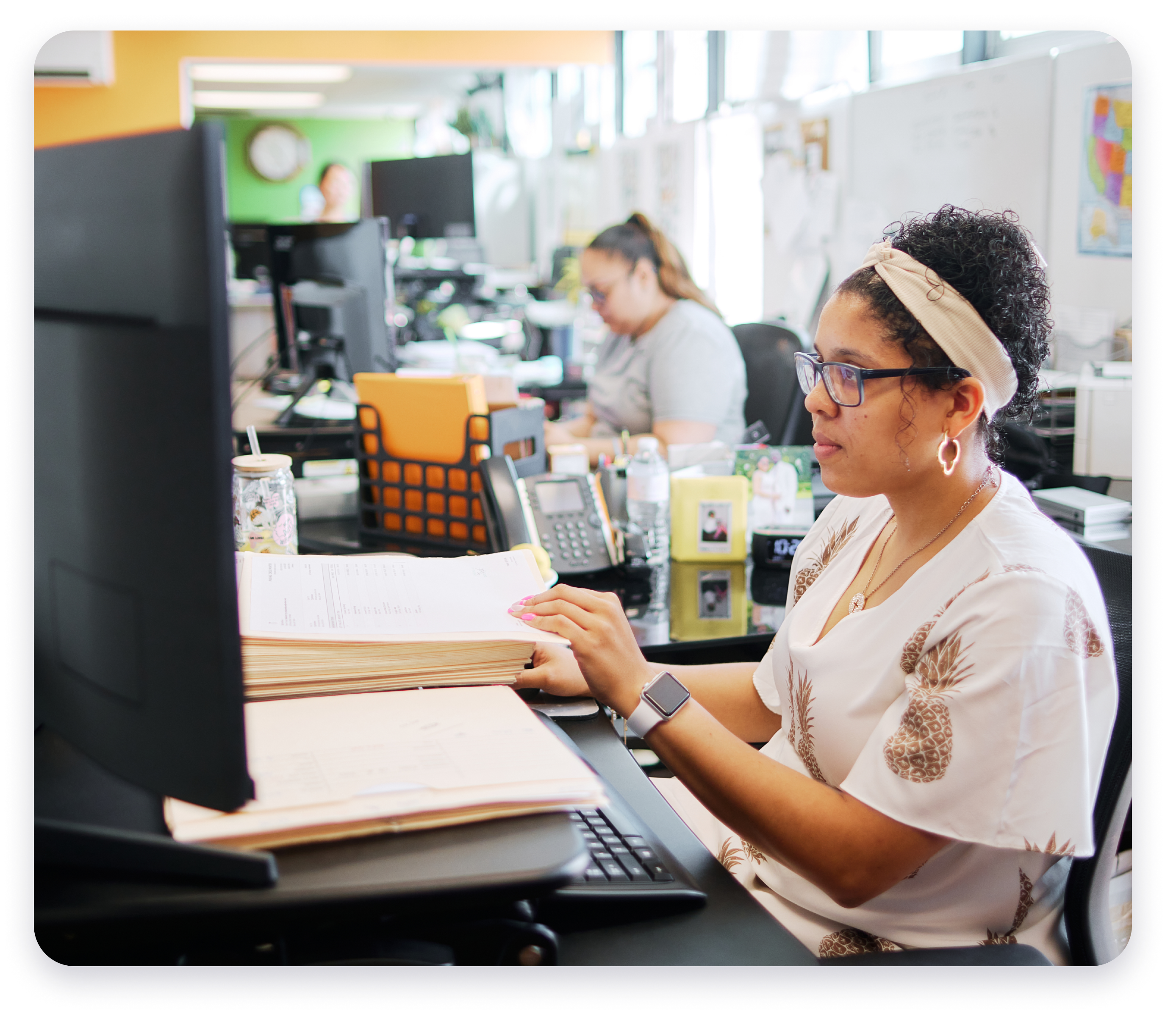 Person using at a computer checking paper invoices