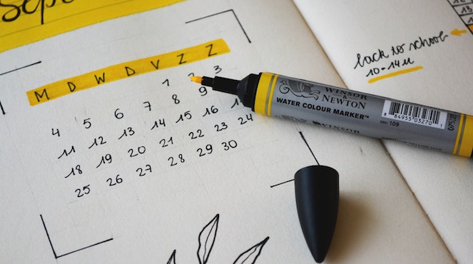 Yellow highlighter sitting on top of a calendar