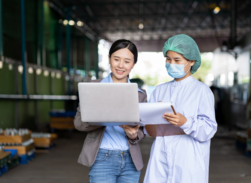 Business woman and produce worker meeting with laptop and clipboard in hand
