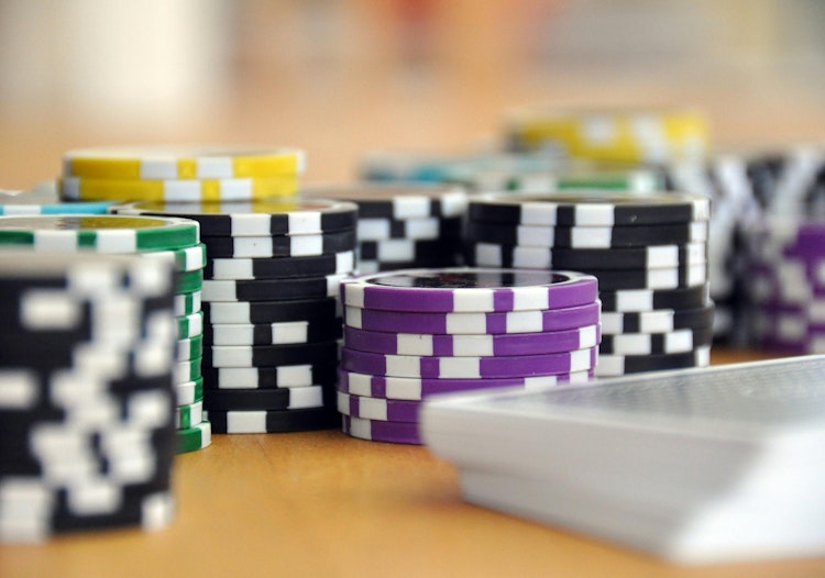 Stacks of colorful casino chips arranged on a table beside a deck of cards.