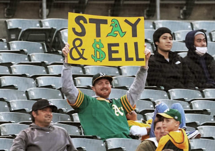 An Oakland Athletics fan holds up a "sell the team" sign.