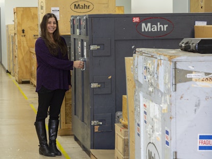 Carly, standing in the Mahr warehouse, closes a massive metal shipping container.