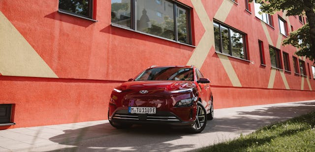 Ein rotes Elektroauto vor einer Hauswand.