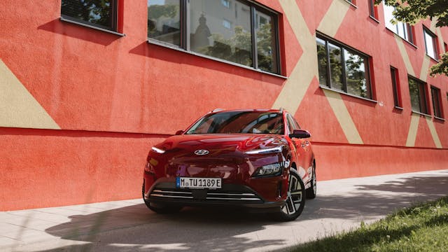 Ein rotes Elektroauto vor einer Hauswand.