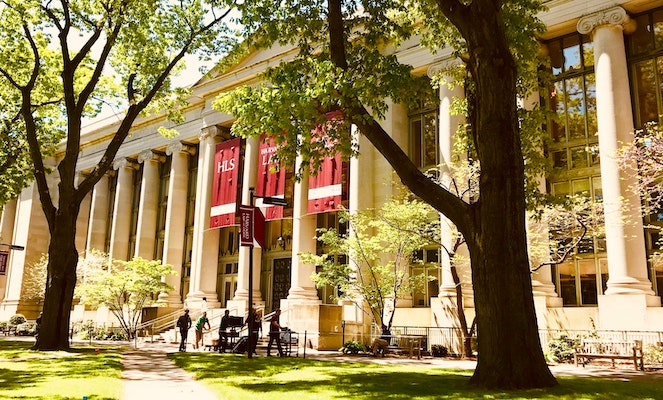 Pillared entrance of university building with trees and grass in front