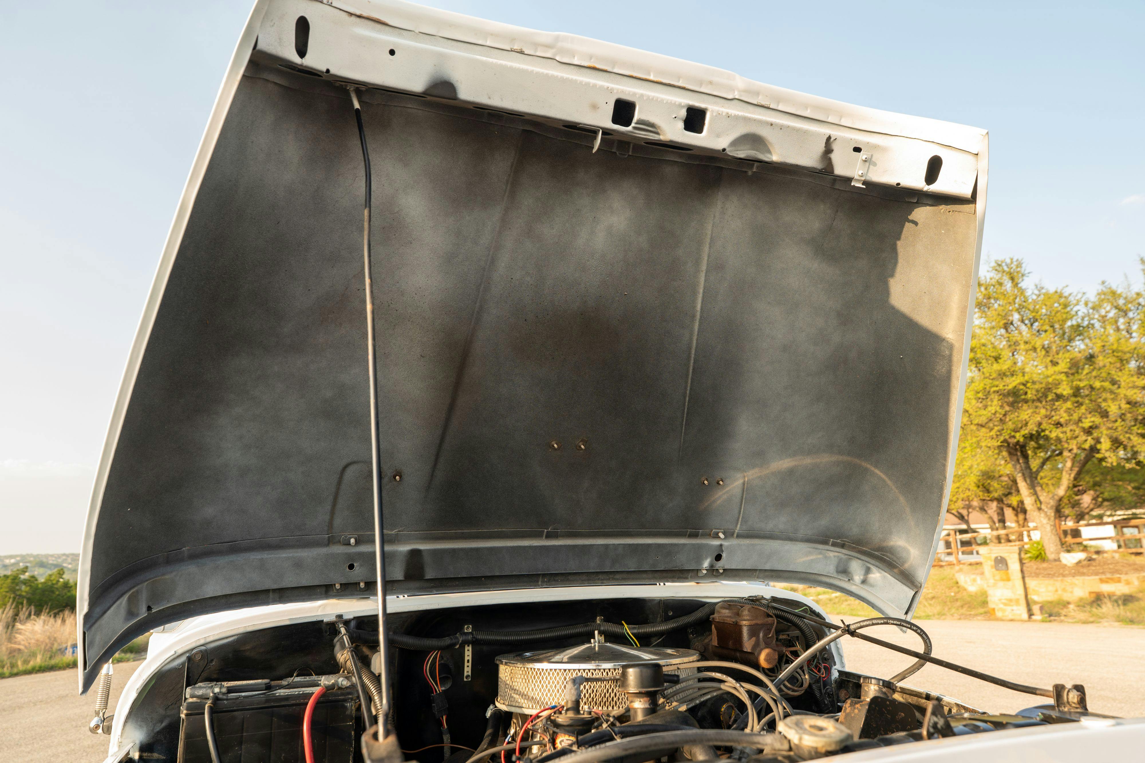 Engine bay of a 1983 Jeep Scrambler in White on Black in Austin, TX.