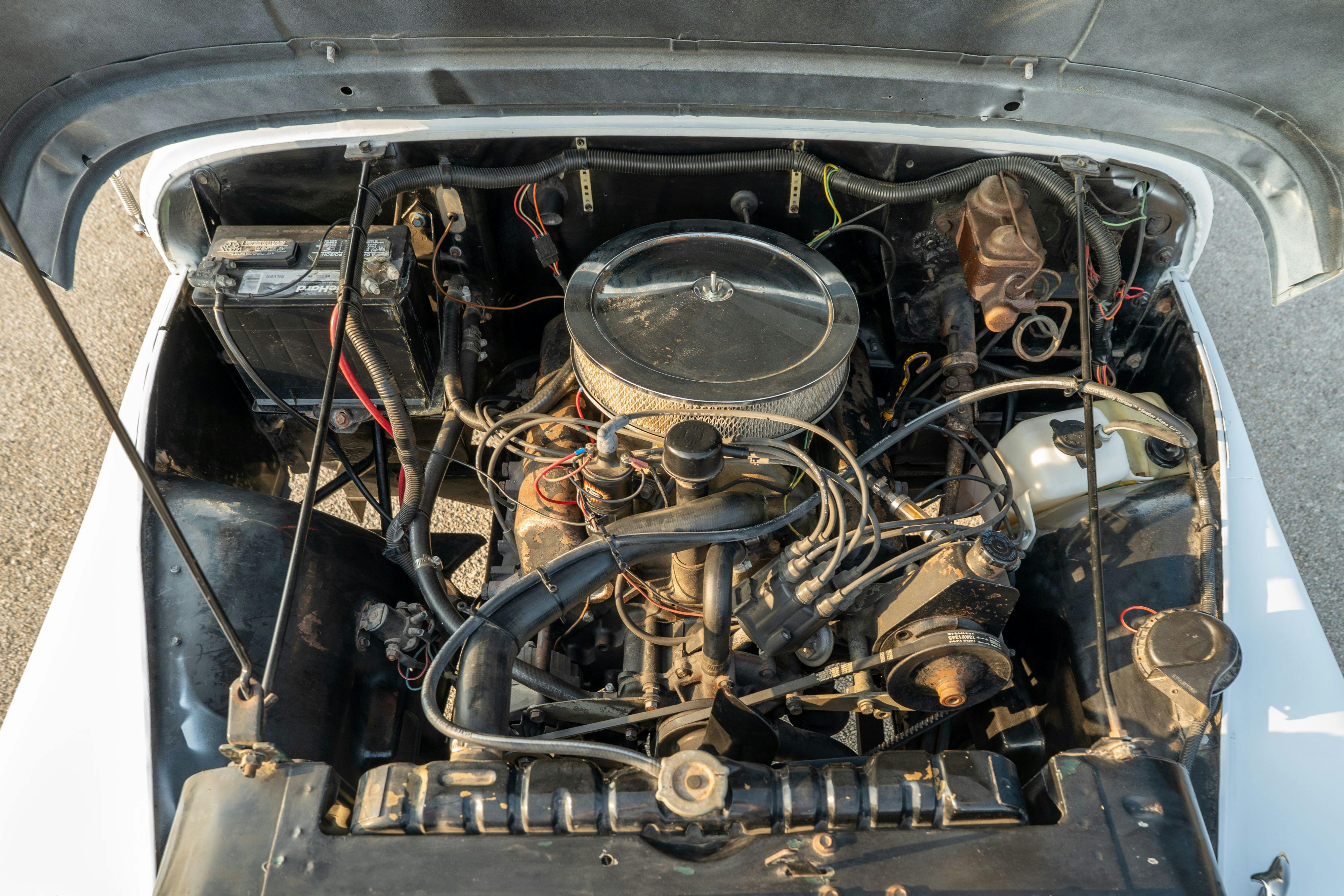 Engine bay of a 1983 Jeep Scrambler in White on Black in Austin, TX.