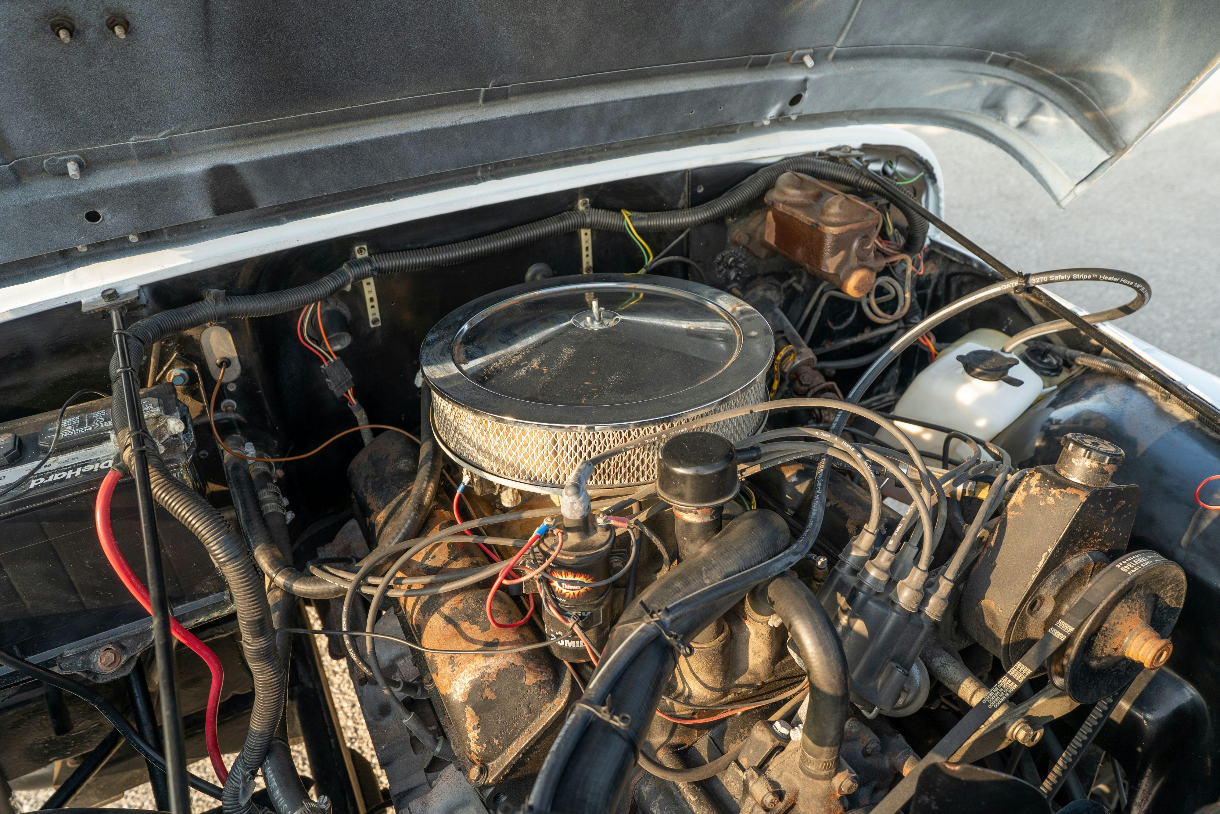 Engine bay of a 1983 Jeep Scrambler in White on Black in Austin, TX.