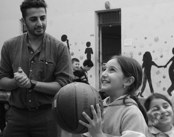 Young girl smiling as she's about to shoot a basketball at recess