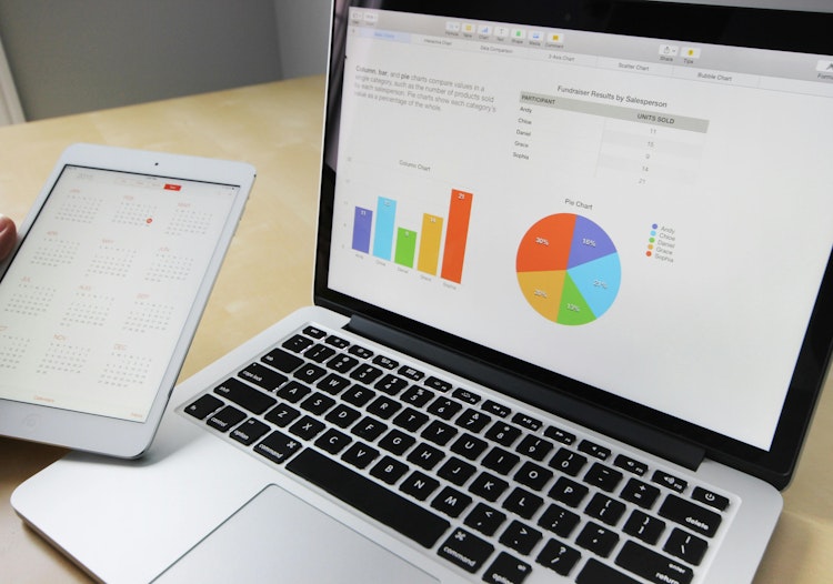Laptop showing charts and analytics beside a tablet with a calendar.