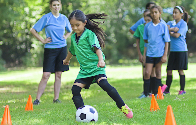 Young girl dribbling a soccer ball during a practice drill