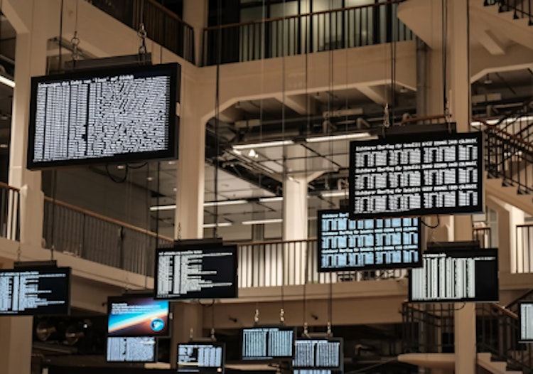 Multiple suspended monitors display streams of real-time data inside a modern tech facility, representing how artificial intelligence and big data power analytics for industries like online sports betting and iGaming.