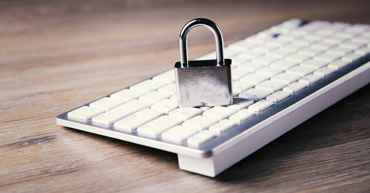 A silver padlock resting on a white computer keyboard on a wooden surface, symbolizing cybersecurity and digital data protection.