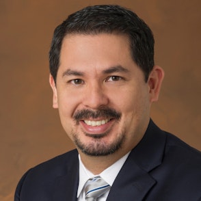 David, a Hispanic man, smiles for an official headshot in a formal suit.