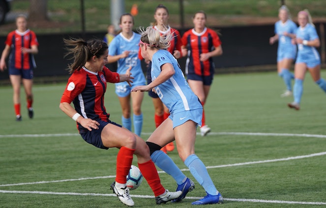 Opposing women's soccer players battle for the ball during a match