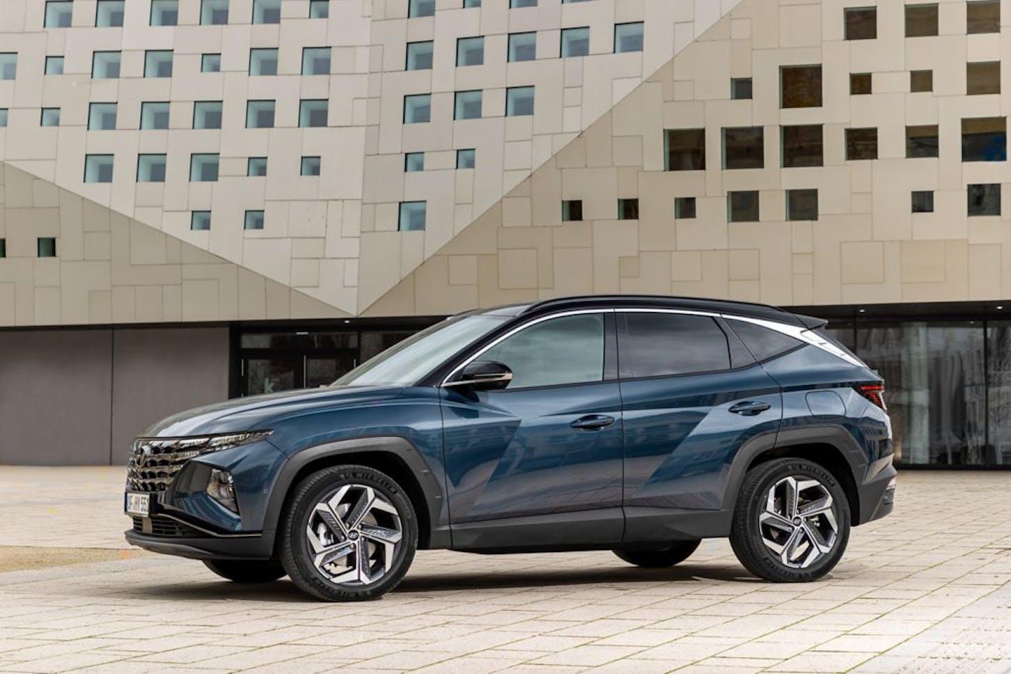 Der Hyundai Tucson Hybrid steht vor einem Gebäude.