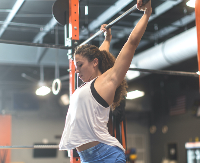 Young woman about to do a pull-up at the gym