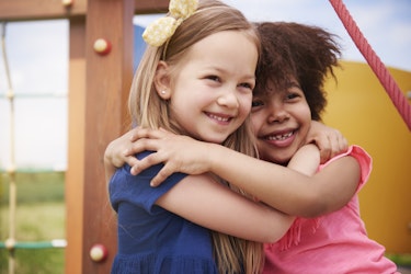 two happy girls hugging and smiling on the playground