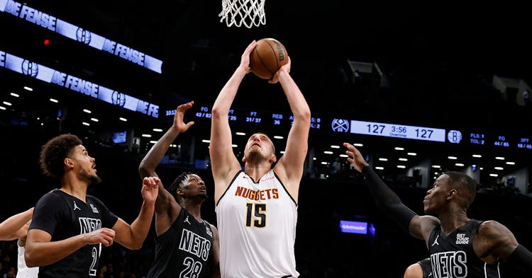 Nikola Jokic shooting a layup with three defenders on him.