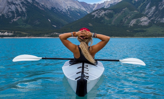 Woman taking a rest in her kayak on a mountainside lake