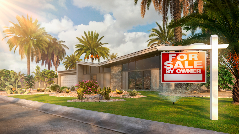 Home with palm trees and for sale sign
