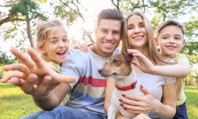 Family with two small kids taking a photo with their Fox terrier puppy.
