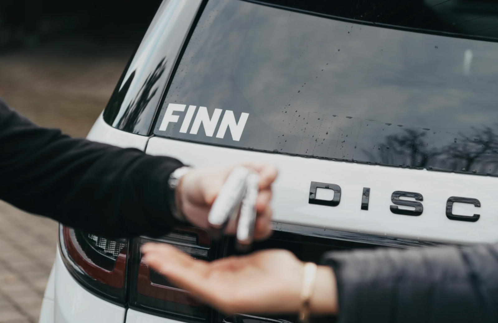 Schlüsselübergabe vor einem FINN Auto.