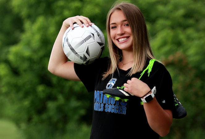 Young female student athlete poses outdoors with her soccer ball and shoes