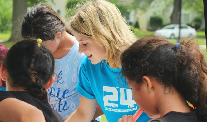 Young woman smiling while leading a group of girls doing community service